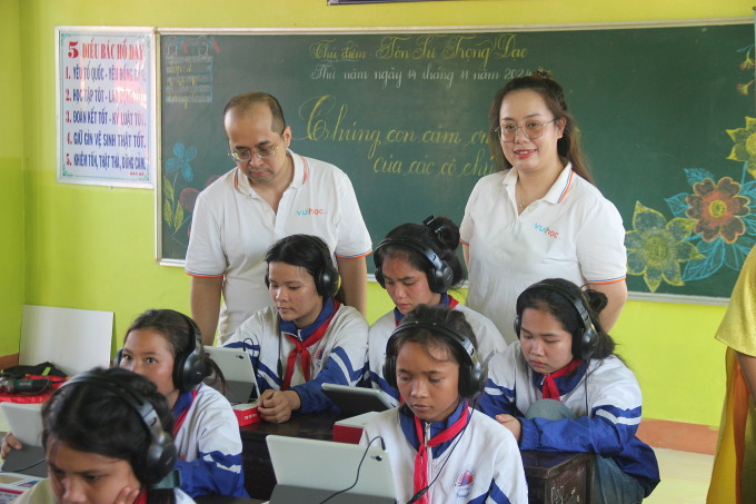 Cán bộ nhân viên Công ty Vuihoc hướng dẫn học sinh tại điểm trường Hrach sử dụng thư viện điện tử. Ứng dụng Vuihoc được xây dựng và thiết kế giúp học sinh và giáo viên tương tác hai chiều, với nhiều dạng học liệu: Video, kể chuyện, dự án, thử thách bản thân. Lộ trình học tập được xây dựng theo Sách giáo khoa cải cách. Ảnh: Trần Hóa