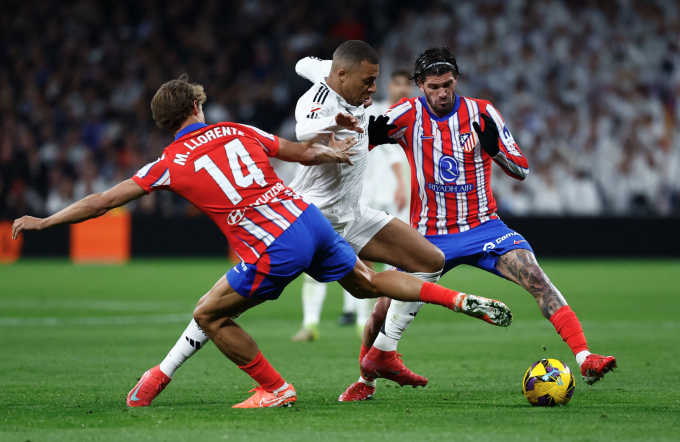 Kylian Mbappe đi bóng giữa vòng vây của Marcos Llorente và Rodrigo De Paul ở trận Real hòa Atletico 1-1 vào ngày 9/2. Ảnh: Reuters