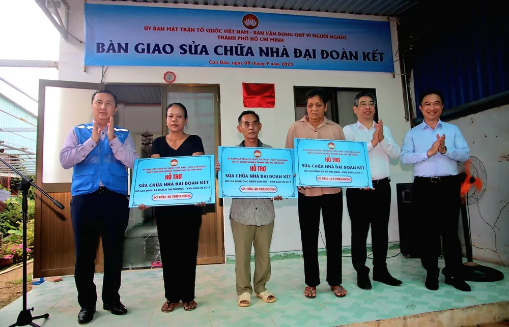 Lãnh đạo Thành ủy TP.HCM trao tặng bảng tượng trưng bàn giao sửa chữa nhà Đại đoàn kết cho 3 hộ dân. Ảnh: HD Đoàn công tác TP.HCM.JPG