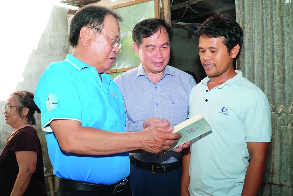 Ông Phan Xuân Thủy, Phó Trưởng ban Tuyên giáo và Dân vận Trung ương (giữa), cùng ông Mai Ngọc Phước, Tổng Biên tập báo Pháp Luật TP.HCM, giới thiệu với ngư dân Ninh Thuận về cẩm nang “Những điều cần biết về đánh bắt hải sản” vào ngày 14-6-2023. Ảnh: BẢO PHƯƠNG P2021_Cot phai_h1.jpg