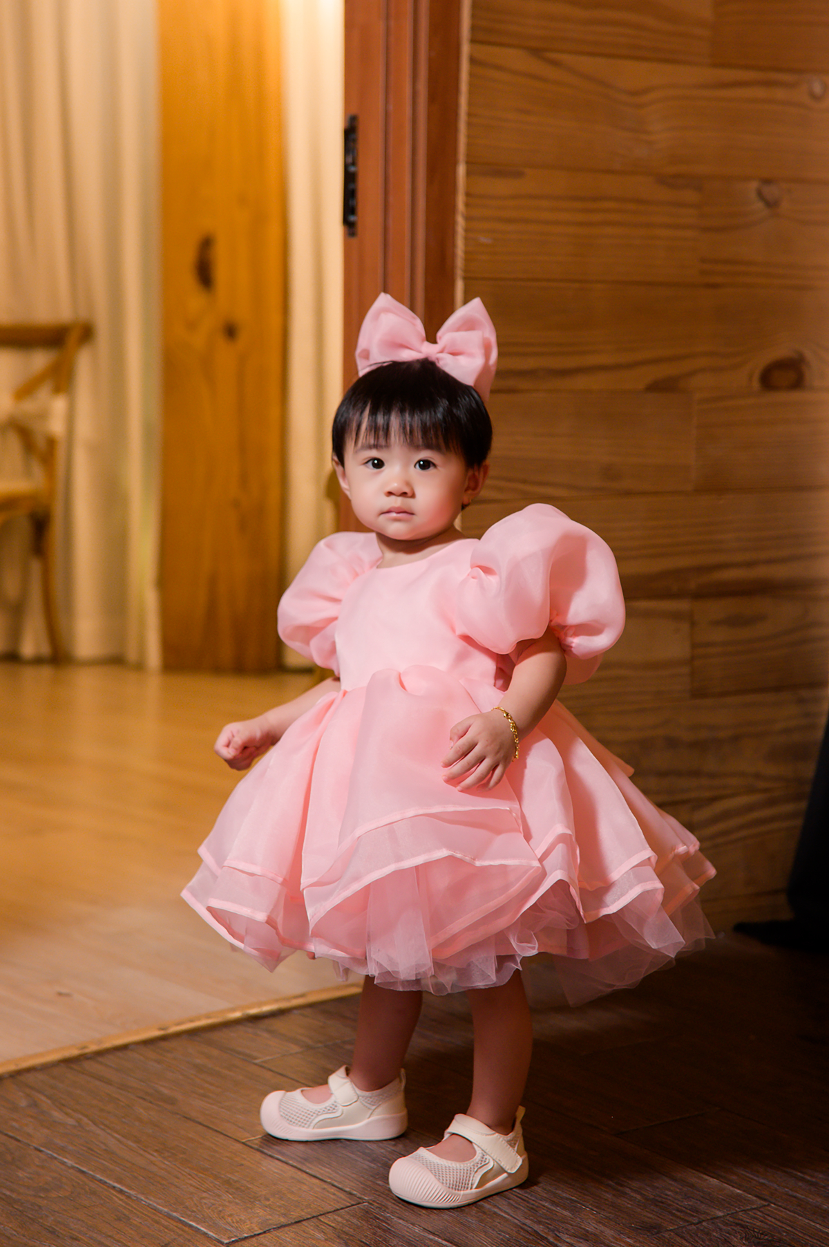 Bé Nubi được mẹ cho diện váy công chúa điệu đà, cài nơ tiệp màu, đeo vòng tay bằng vàng 18K và phối giày trắng.