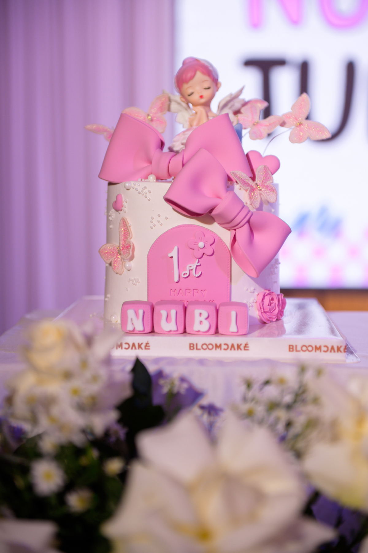 Chiếc bánh kem trang trí nơ, hoa và cánh bướm được đặt trước hơn một tuần nhằm đảm bảo đúng concept buổi tiệc.