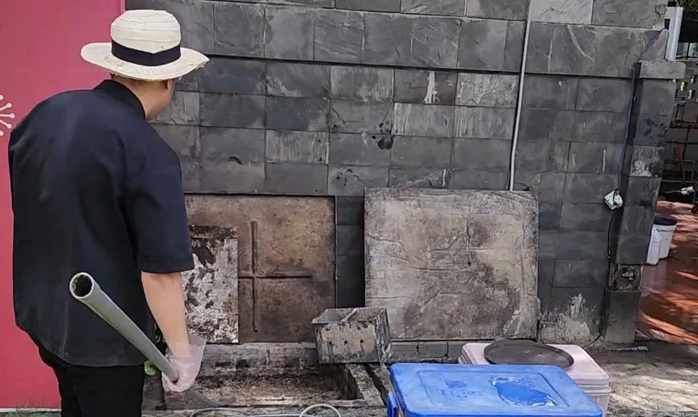 Một nhân viên của cơ sở lưu trú mở nắp cống để xả nước tràn ra bờ biển Mỹ Khê hồi tháng 4-2025. Ảnh: MINH TRƯỜNG. xa-nuoc-thai-ra-bien.jpg