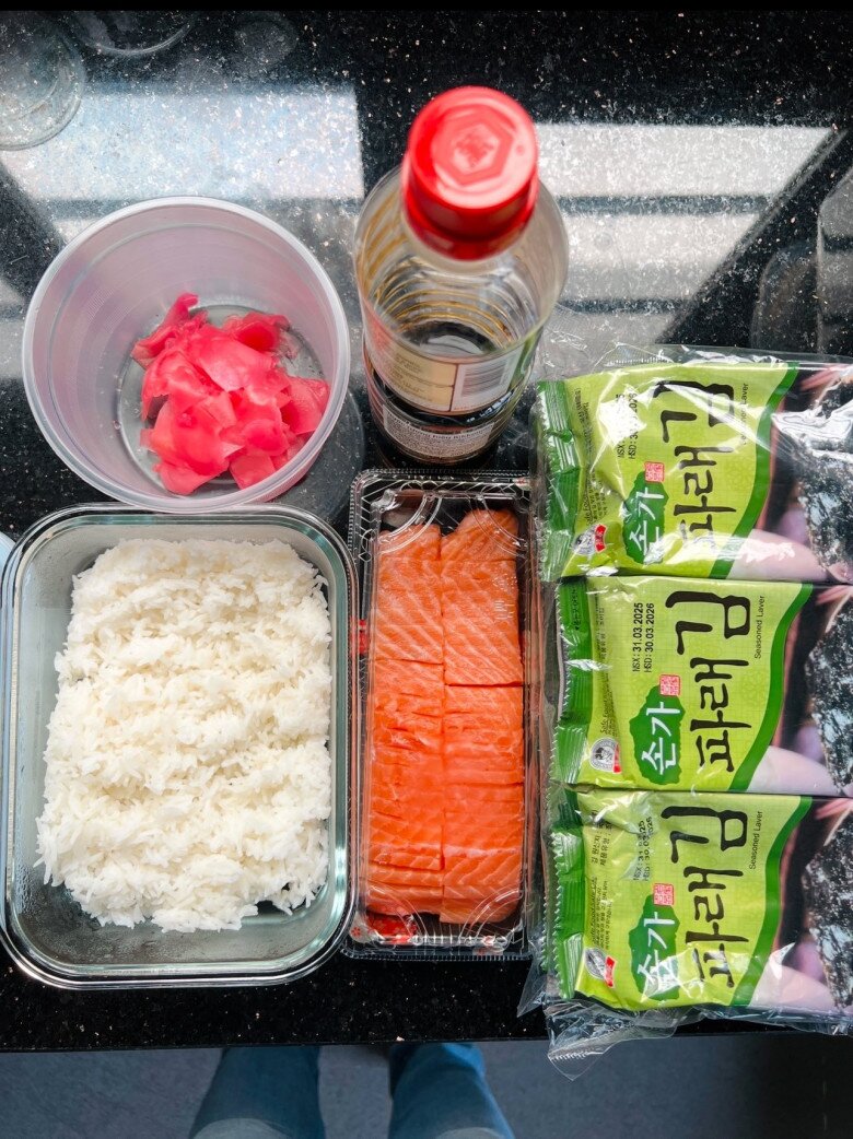 Đầy đủ nguyên liệu cho một bữa sashimi cá hồi cuốn rong biển: Cơm dẻo, cá hồi, gừng hồng, nước tương Nhật và 3 gói rong biển vị truyền thống, tất cả đều nam đại gia được chuẩn bị kỹ lưỡng.