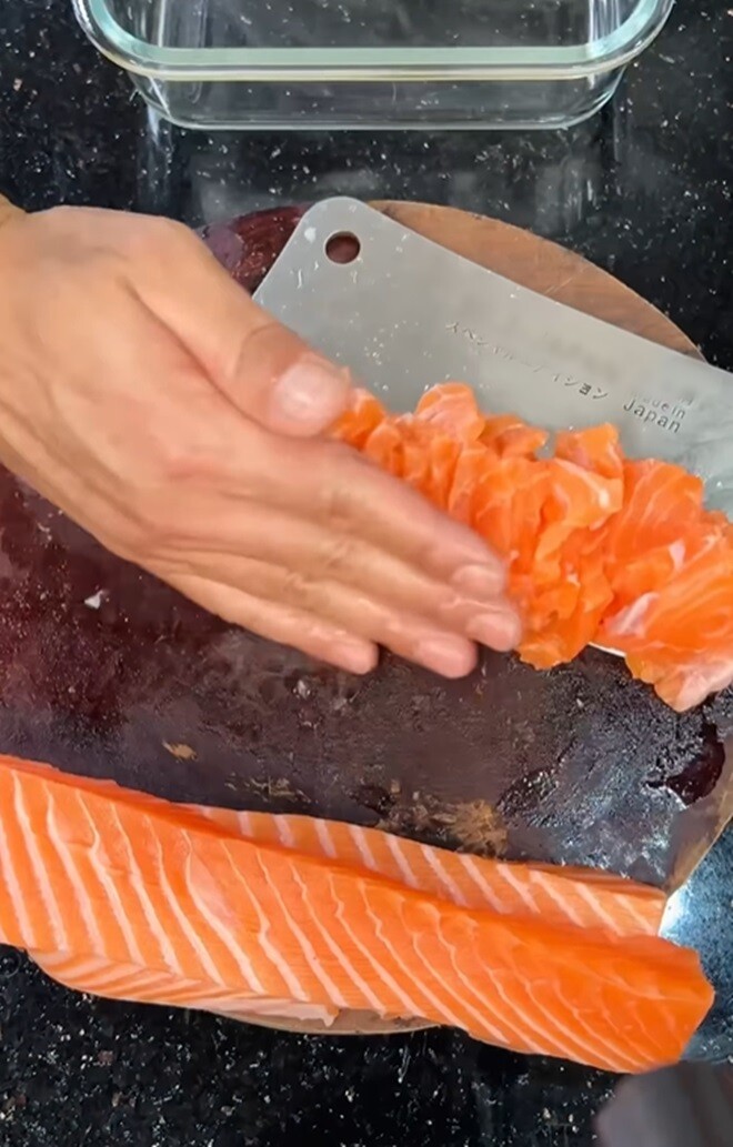 Thắng Ngô tự tay thái cá hồi sashimi với dao chuyên dụng. Từng lát cá đều tăm tắp, cho thấy sự khéo tay của một ông bố tuy “nghiệp dư” nhưng cực kỳ tận tâm.