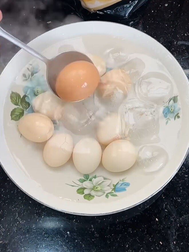 Tiếp đó là luộc trứng. Anh luộc 10 quả, khi nước sôi thì để hạ lửa nhỏ cho sôi liu riu tầm 4-5 phút. Sau đó anh vớt vào trong tô nước đá để bóc vỏ được dễ dàng.