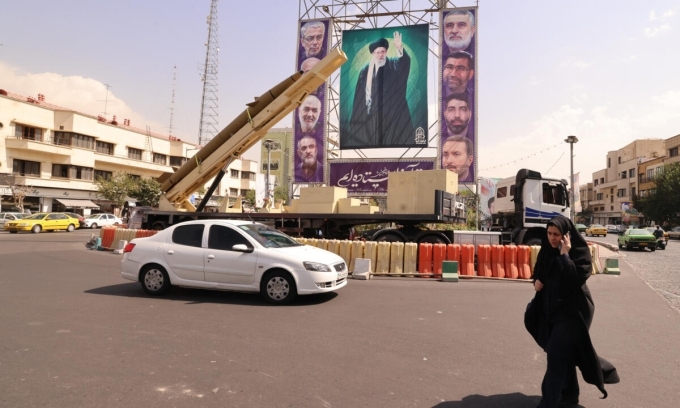 Người phụ nữ đi ngang khu vực trưng bày tên lửa đã ngừng hoạt động và một bức chân dung khổng lồ của Lãnh tụ Tối cao Iran Ayatollah Ali Khamenei ở Tehran hôm 27/9. Ảnh: AFP