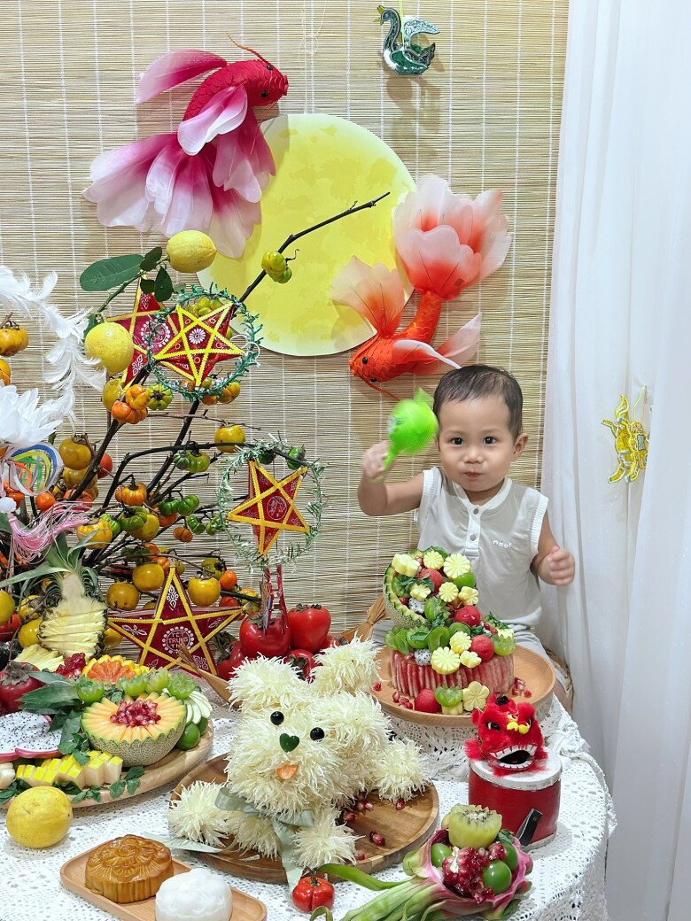Em bé nhà chị Thủy rất thích thú với mâm cỗ Tết Trung thu mẹ làm. Mâm cỗ gồm có chó bưởi, các loại trái cây được tỉa đẹp mắt, hồng, bánh Trung thu, đèn ông sao...