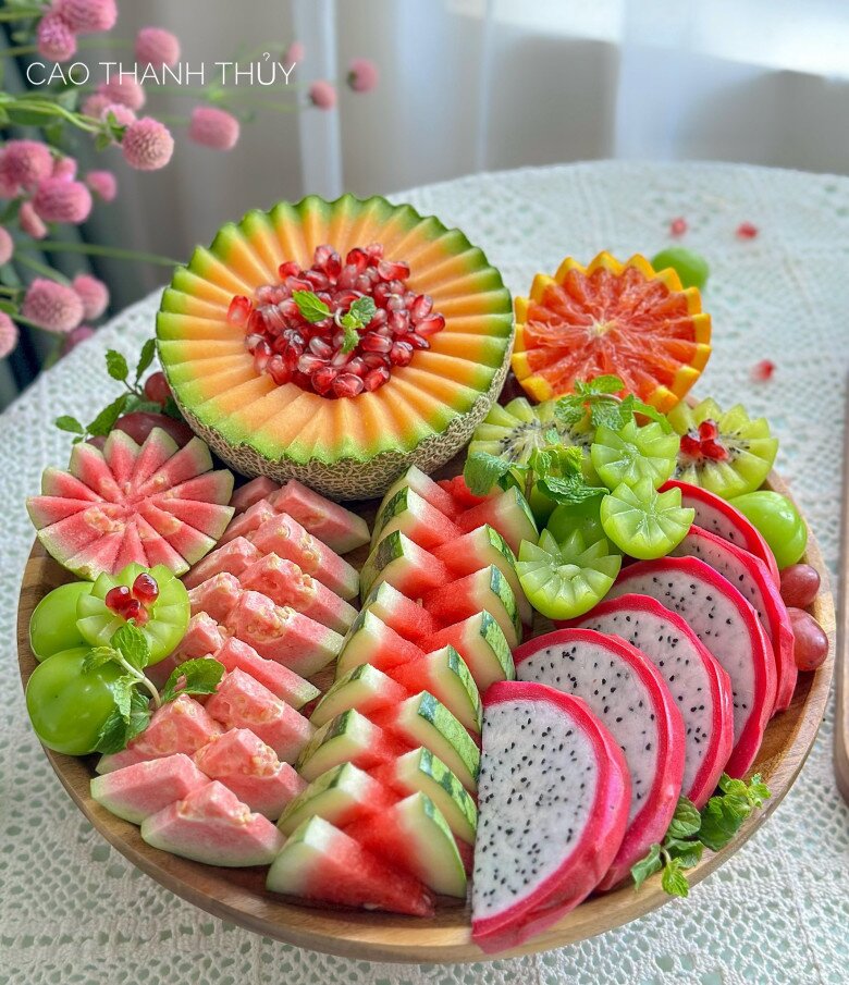 Dưa hấu, bưởi hồng, thanh long được chị Thủy cắt lát và xếp so le nhau trông rất bắt mắt. Trong đó dưa lưới, cam, nho, cũng được tỉa hoa đơn giản mà ấn tượng. Một mẹt quả giống như một vườn hoa vậy.