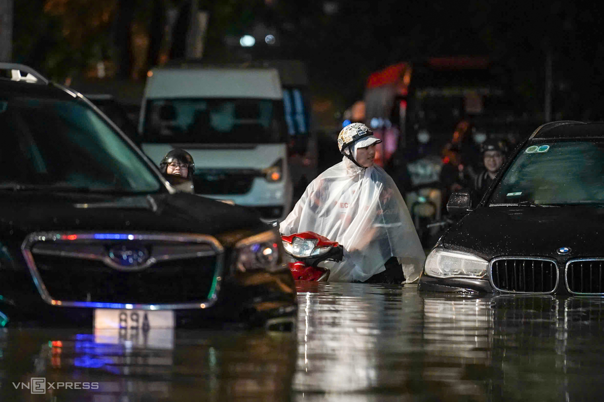 Người dân dắt xe máy tại ngã tư Thái Hà - Láng Hạ, giữa hàng loạt ôtô ngập nước bỏ lại trên đường. Ảnh: Hoàng Giang