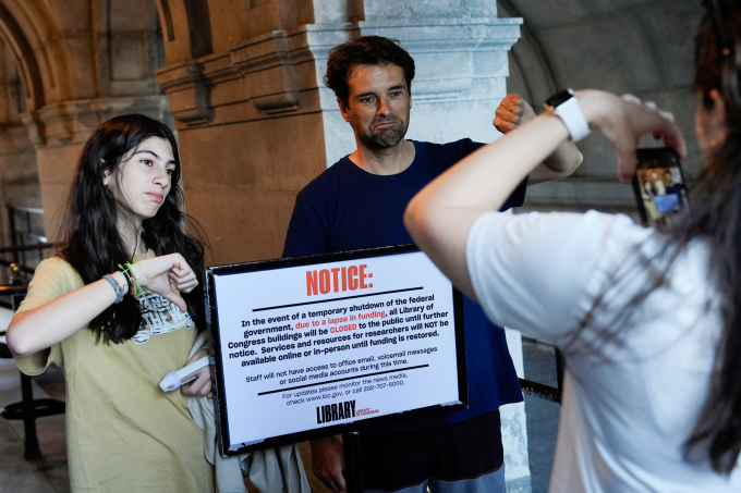 Người dân Mỹ chụp ảnh trước bảng thông báo Thư viện Quốc hội Mỹ đóng cửa ngày 1/10. Ảnh: AP