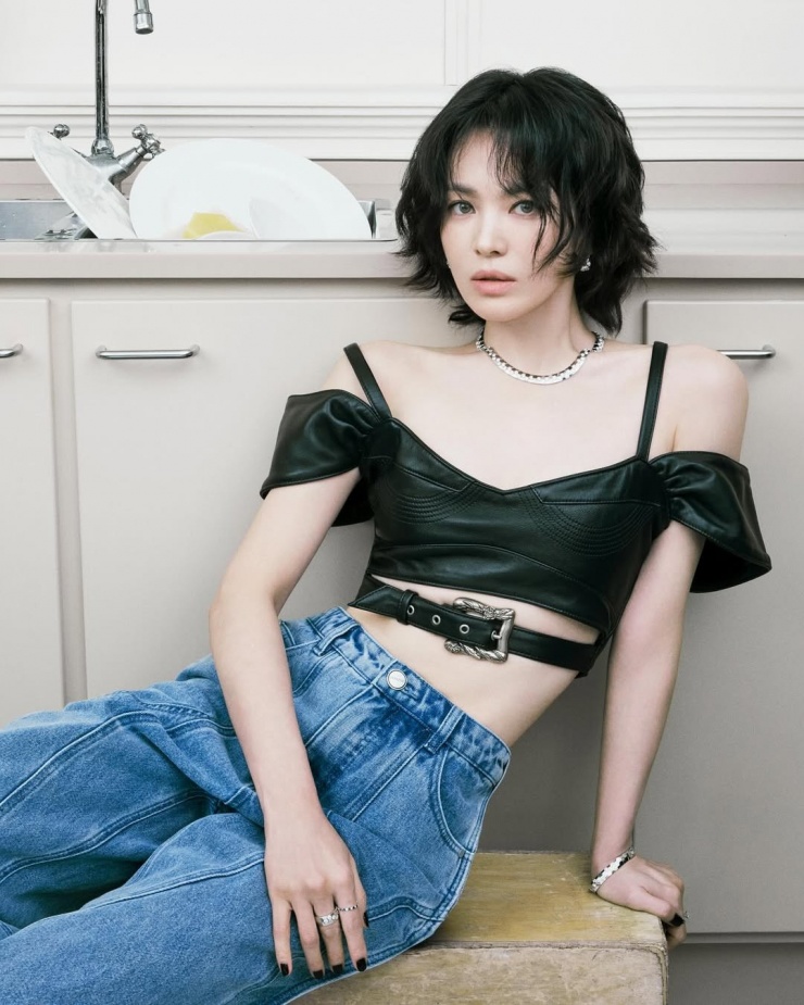 Hye Kyo mặc crop top da trễ vai, phối cùng quần jeans ống rộng, trang điểm tạo vẻ hoang dại.