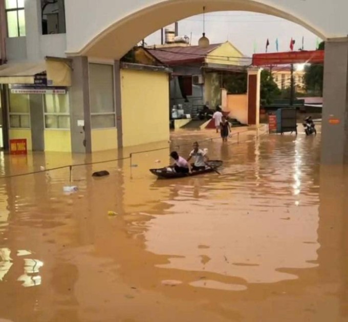 Đi lại trong sân trung tâm y tế phải dùng thuyền do mực nước dâng cao. Ảnh: BVCC