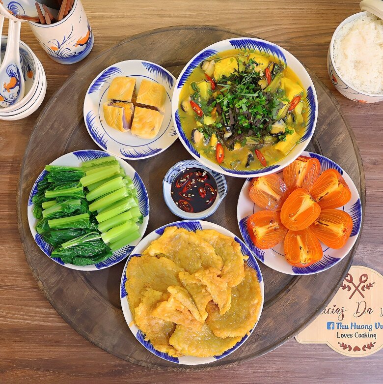 Mâm cơm này gồm các món: Chả trứng chiên cốm, ốc nấu chuối đậu, cải mèo luộc.