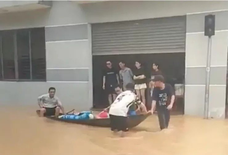 Đưa các nạn nhân trong gia đình ngạt khí ra khỏi khu vực ngập để cấp cứu. (Ảnh: Ngọc Thi)