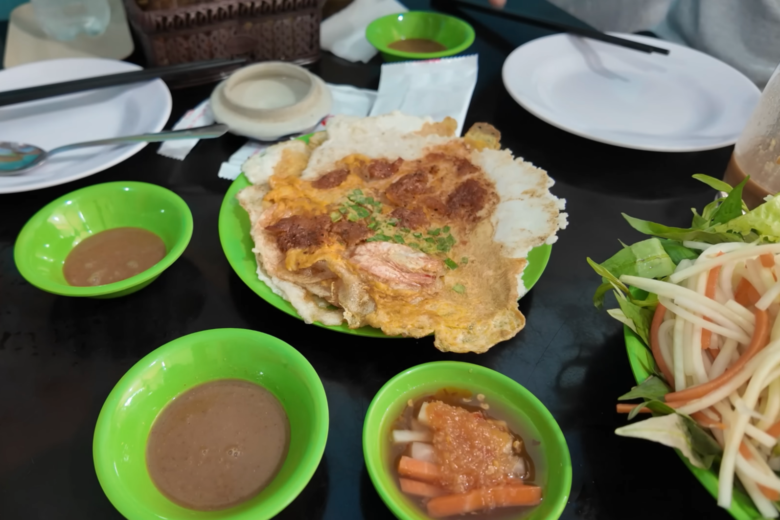 Bánh ép nóng hổi ăn kèm rau răm, xà lách, đu đủ, cà rốt muối chua. Ảnh: Chad Kubanoff