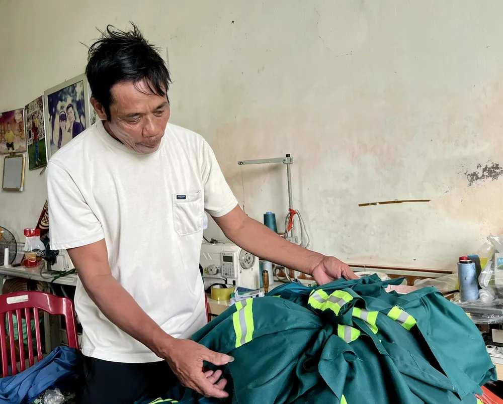 Ông Từ rà lại xấp vải đã bị cơn lốc xoáy cuốn đi, còn ướt sũng, hôi mùi nước bẩn. Ảnh: TT cơn lốc xoáy