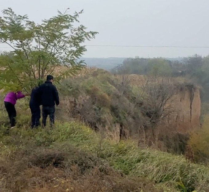 Gia đình đứng bên vực, nhìn xuống nơi Lan bị chồng ném xuống. Nạn nhân được cơ quan chức năng dùng dây thừng kéo lên nhưng đã tử vong. Ảnh: Shangyou