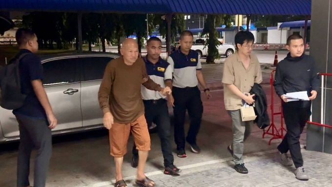 Cựu trụ trì Phra Ratchawisutthiprachanat (áo nâu) bị CIB dẫn giải. Ảnh: Nation