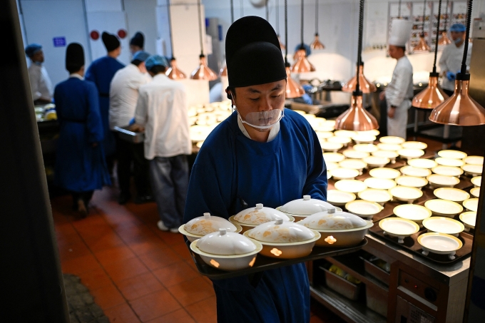 Nhân viên mặc trang phục thái giám bê thức ăn trong bếp của nhà hàng theo chủ đề cổ đại ở Bắc Kinh ngày 5/11. Ảnh: AFP