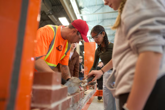 Một nữ sinh lớp 8 (áo nâu, đeo kính bảo hộ) học trát vữa tại hội chợ nghề ở London, Ontario, Canada. Ảnh: Globe and Mail