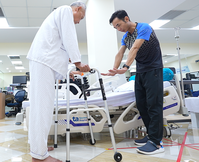 Chuyên viên vật lý trị liệu hướng dẫn ông Trúc đi lại sau ca phẫu thuật lần thứ năm. Ảnh: Bệnh viện Đa khoa Tâm Anh