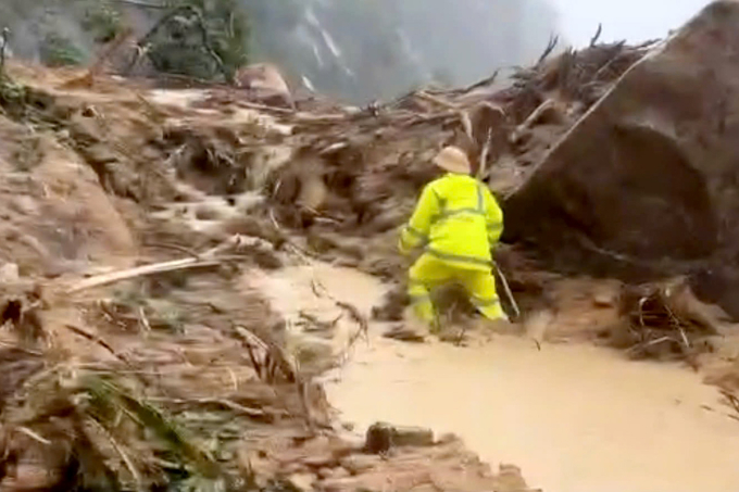 Một CSGT trong tổ cứu hộ băng qua đoạn sạt lở đèo. Ảnh: Công an Lâm Đồng