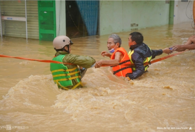 Người dân Nha Trang được lực lượng chức năng hỗ trợ qua dòng nước xiết. Ảnh: Bùi Toàn