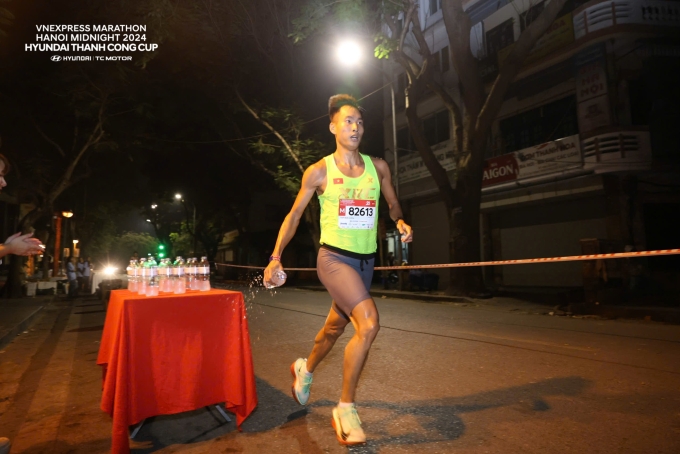 VĐV Trịnh Quốc Lượng tiếp nước tại trạm ở giải chạy đêm 2024. Ảnh: VnExpress Marathon