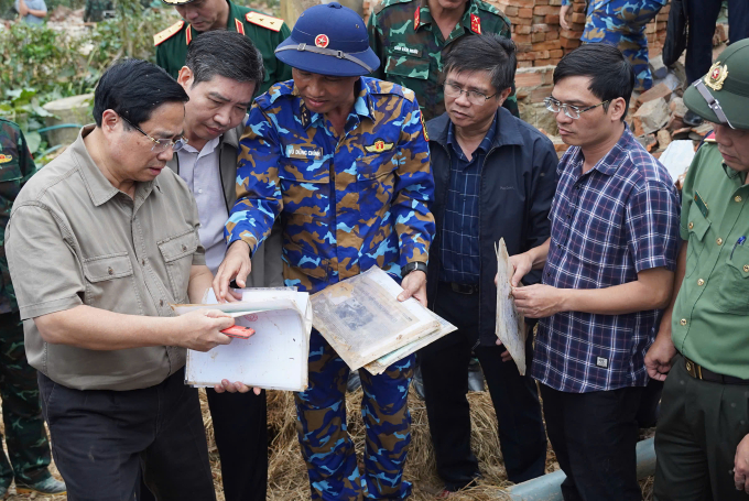 Thủ tướng xúc động xem những vật dụng của người dân còn sót lại sau lũ lụt - Ảnh: Bùi Toàn