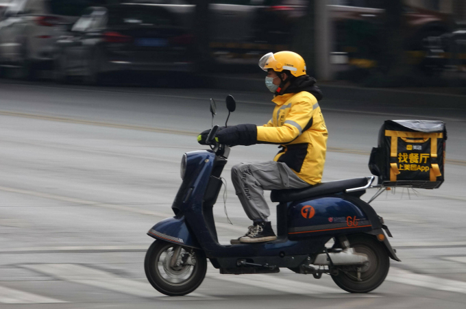 Một shipper  đang giao đồ ăn cho khách hàng bằng xe máy điện trên đường phố Trung Quốc. Ảnh: Sohu