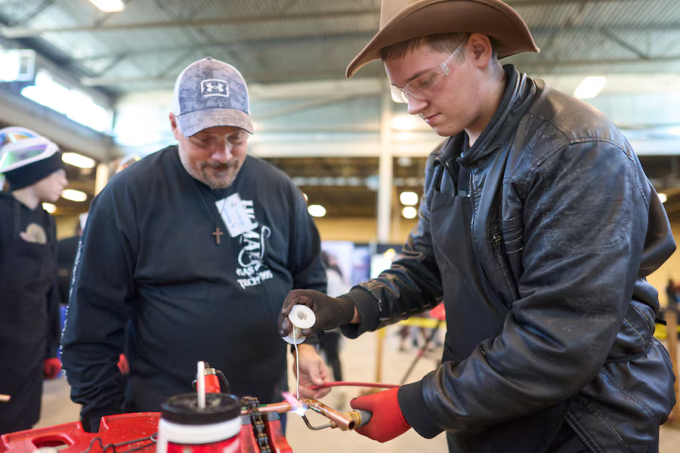 Daniel Friesen (mặc áo da) học hàn ống đồng tại hội chợ nghề ở Ontario, Canada. Ảnh: Globe and Mail