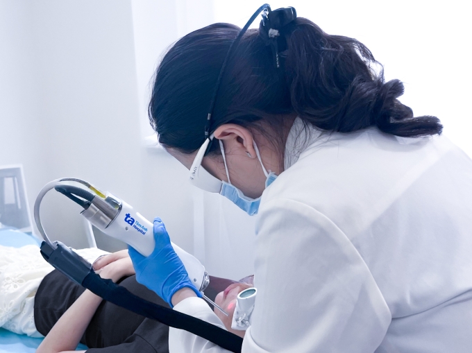 Bác sĩ Trang sử dụng laser Nd:YAG xung dài giảm mụn viêm và hồng ban sau mụn cho chị Hằng. Ảnh: Bệnh viện Đa khoa Tâm Anh