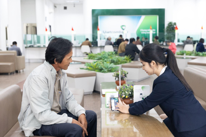 Nhân viên ngân hàng hướng dẫn khách hàng gửi tiết kiệm online. Ảnh: Vietcombank