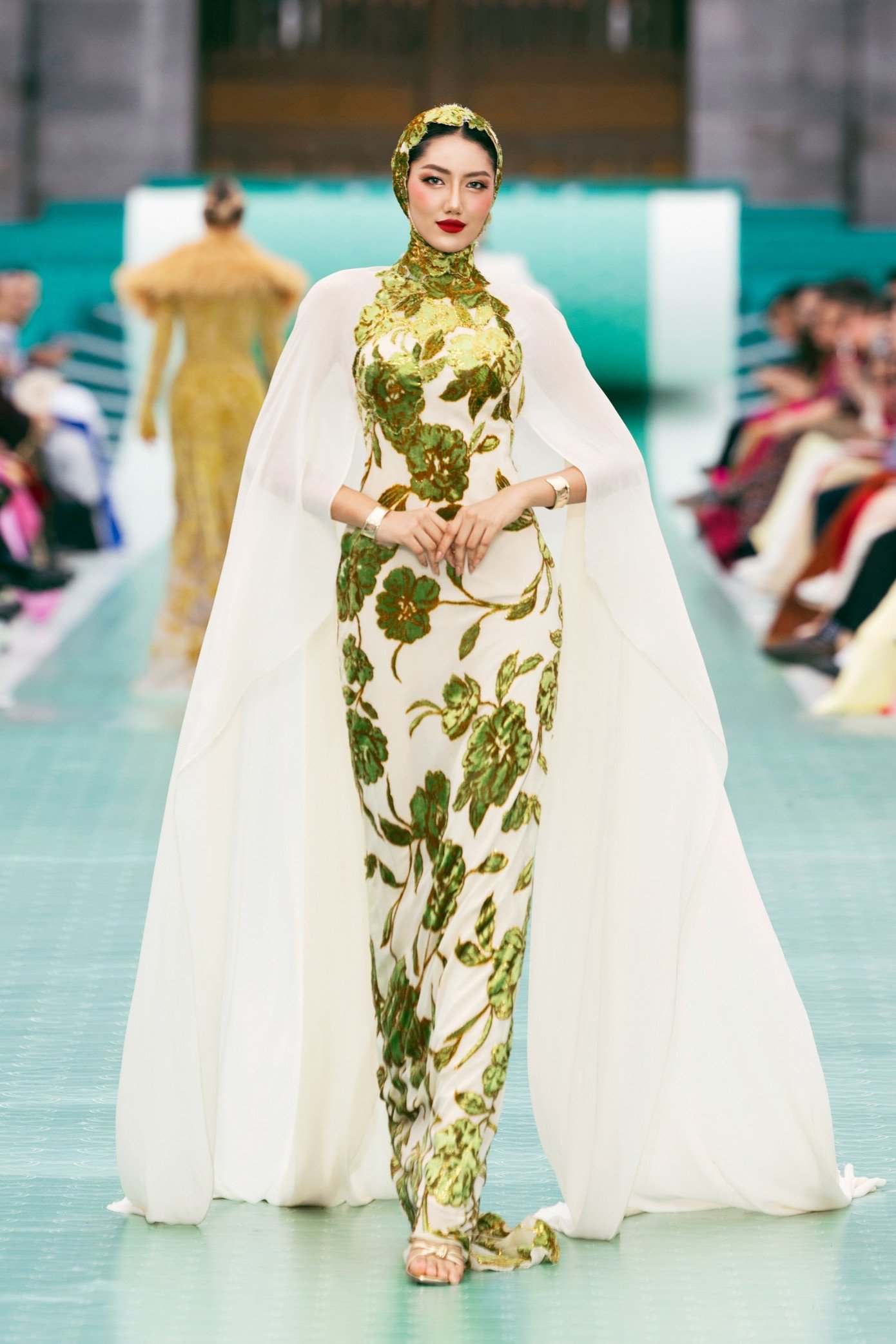 NTK Lê Thanh Hòa khéo léo chuyển tải hình ảnh tường thành rêu phong, mái ngói cổ kính, khung cửa chạm rồng phượng, cùng các giá trị thủ công truyền thống: Sơn mài, Pháp lam, thêu cung đình, tranh kính, hay trang phục truyền thống như áo Ngũ Thân, Nhật Bình. Tất cả được tái hiện qua kỹ thuật hiện đại, tạo nên một khúc giao hưởng đặc biệt giữa di sản và phong cách đương đại.