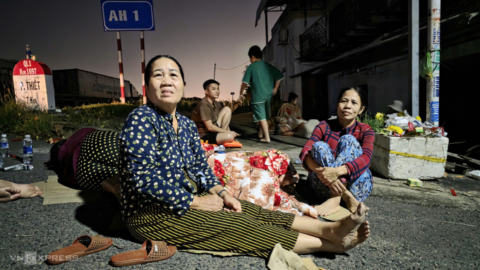 Bà Thoa (bên trái) cùng con gái và nhiều người ra khu vực quốc lộ 1 gần chân cầu Phú Long lánh nạn, khuya 4.12. Ảnh: Phước Tuấn