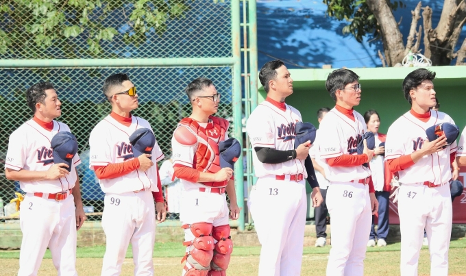 Thành viên đội tuyển bóng chày nam Việt Nam thực hiện nghi thức chào cờ trước trận gặp Lào. Ảnh: BAT