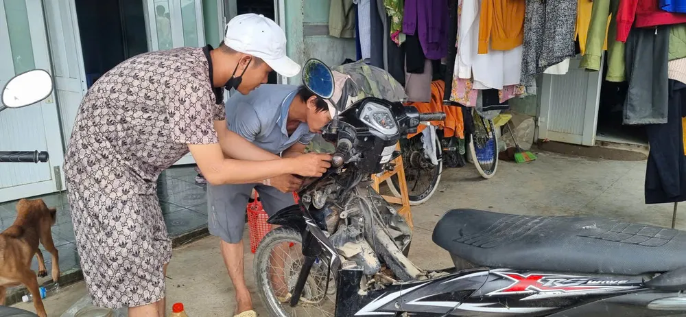 Anh Vũ và bạn sửa xe máy giúp bà con. Ảnh: T.T XE MÁY.jpg