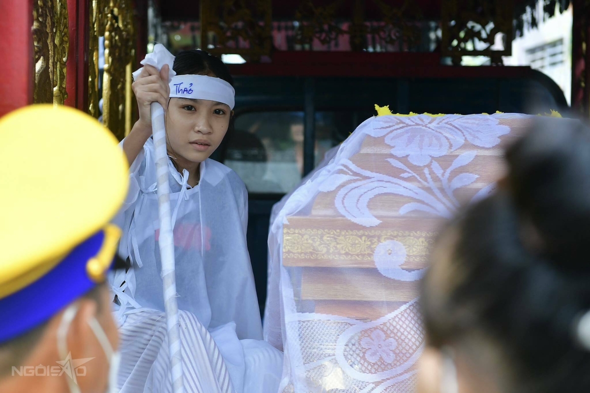 Thạch Thảo, con gái 12 tuổi của Thương Tín ngồi bên cha, thỉnh thoảng đưa mắt tìm mẹ trong đám đông.