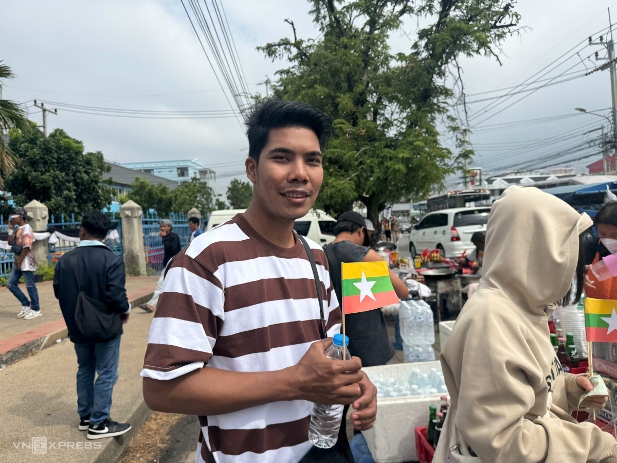 Một CĐV nam Myanmar mua nước và mang theo lá cờ nhỏ chuẩn bị vào sân.