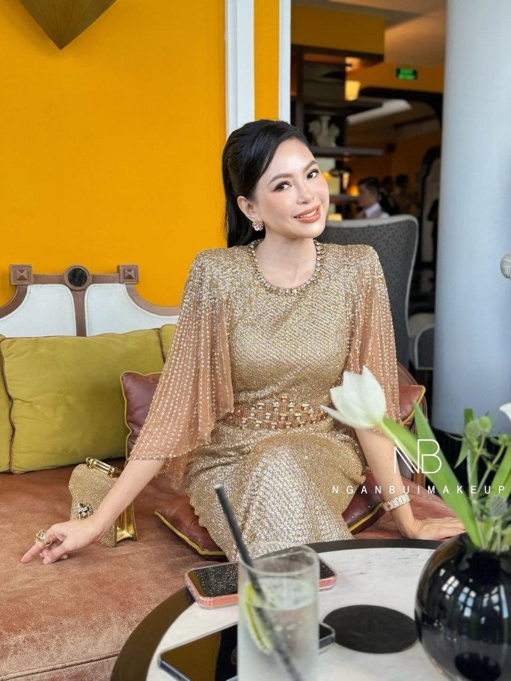 Thiết kế có giá khoảng 5.000 USD (130 triệu đồng), với phần vai độn vuông vức, ống tay loe, nhấn bằng chi tiết đính cườm và đá ở eo. Người đẹp phối trang phục với túi xách cùng tông của Dolce & Gabbana - thương hiệu cô yêu thích và theo đuổi nhiều năm nay. Doanh nhân được chuyên gia Ngân Bùi trang điểm tông cam đất để ăn ý với bộ váy. Ảnh: Ngân Bùi