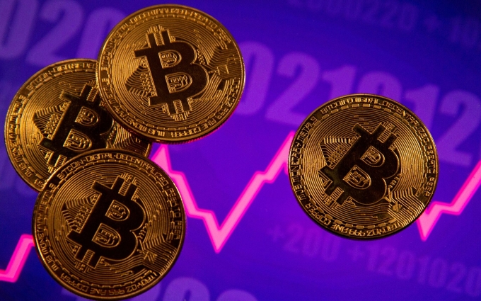 Các biểu trưng của Bitcoin được đặt trên màn hình đồ thị về giá. Ảnh: Reuters