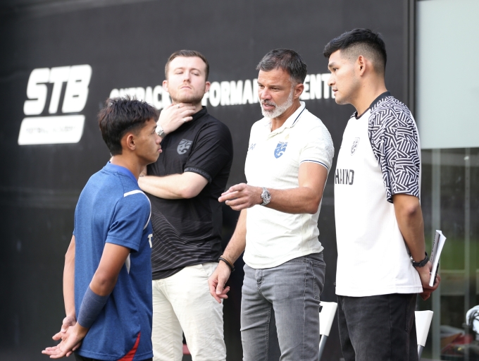HLV Anthony Hudson (thứ hai từ phải sang) trao đổi với tiền vệ Thái Lan Iklas Sanron trước buổi tập tại sân bóng thuộc Học viện STB ở Bangkok vào chiều 17/12/2025, một ngày trước chung kết SEA Games 33. Ảnh: Hiếu Lương