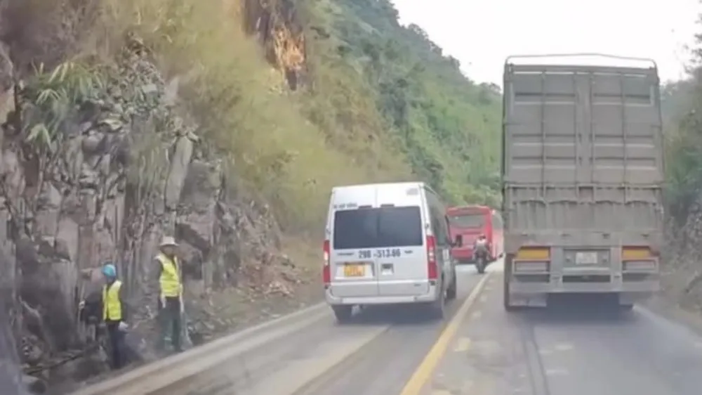 Hai công nhân đứng bên quốc lộ trước khi xảy ra vụ sạt lở thương tâm. Ảnh cắt từ clip camera hành trình. 3-nguoi-tu-vong-sat-lo-quoc-lo-6.jpg