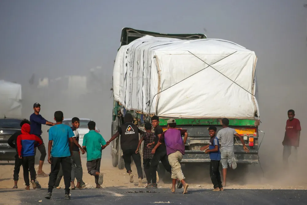 Người dân Gaza đuổi theo một xe cứu trợ ở miền trung Gaza vào ngày 9-11. Ảnh: Eyad Baba/AFP AFP__20251109__83HX8D2__v1__HighRes__PalestinianIsraelConflictAid.jpg