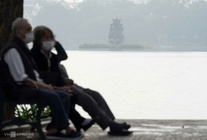 Người cao tuổi đeo khẩu trang ngồi ở Hồ Gươm sáng 2/12. Ảnh: Hoàng Giang