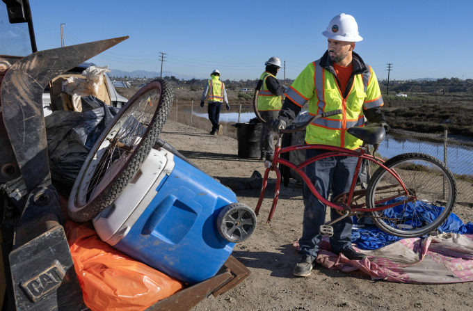 Nhân viên quận Cam dọn dẹp khu lều trại của người vô gia cư dọc đầm lầy sông Santa Ana, ngày 10/12. Ảnh: OC Register