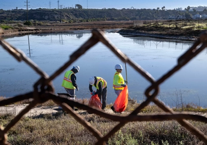 Nhân viên quận Cam dọn dẹp khu lều trại của người vô gia cư dọc đầm lầy sông Santa Ana, ngày 10/12. Ảnh: OC Register