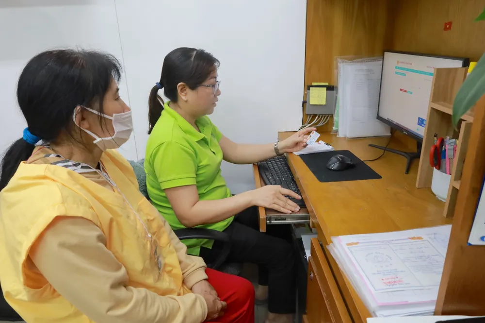 Nhân viên phòng Công tác xã hội Bệnh viện Chợ Rẫy hỗ trợ gia hạn thẻ bảo hiểm y tế hết hạn cho bệnh nhân. Ảnh: DI LINH 1-bảo hiểm y tế .jpg