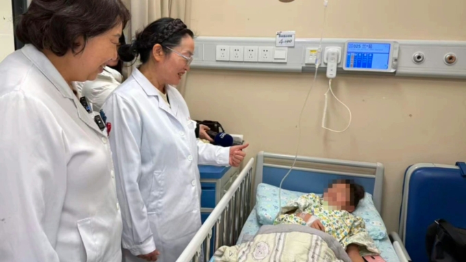 Trước ca phẫu thuật, các chuyên gia đi buồng thăm khám và động viên bé gái. Ảnh: The Paper